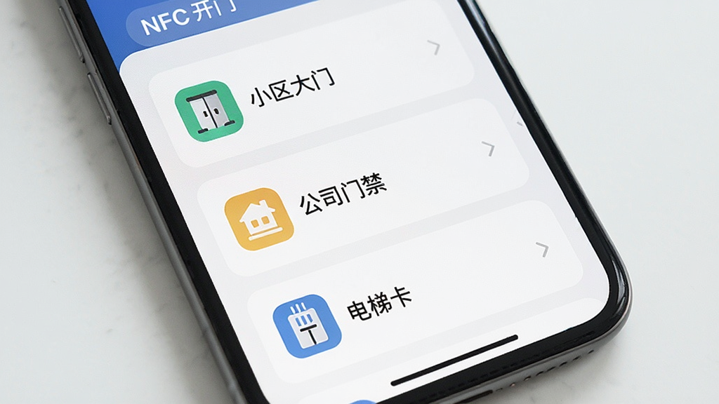手机屏幕显示NFC开门软件的多卡管理界面,列表中有“小区大门”、“公司门禁”、“电梯卡”等卡片名称,每张卡片有独立图标,界面布局清晰,风格现代简约,画质干净,无多余元素。