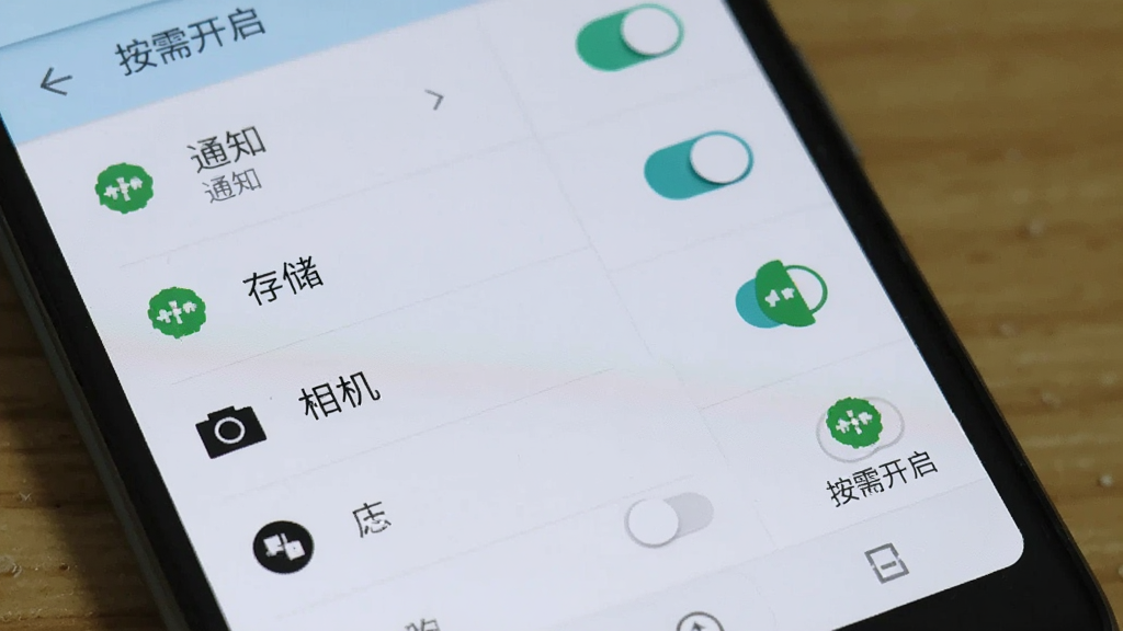 一部安卓手机屏幕显示应用权限设置页面,页面中列出通知、存储、相机等权限开关,旁边有文字标注“按需开启”,背景为浅色系统界面,风格写实清晰,细节包含开关状态与权限图标,画质干净,无多余元素