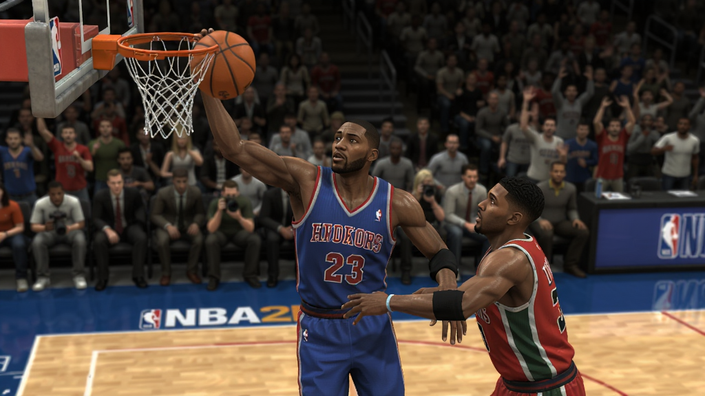 NBA2K9游戏实机画面 显示两名球员在球场上对抗,其中一名球员正在突破上篮,背景是NBA球场和观众,画面逼真,光影效果出色