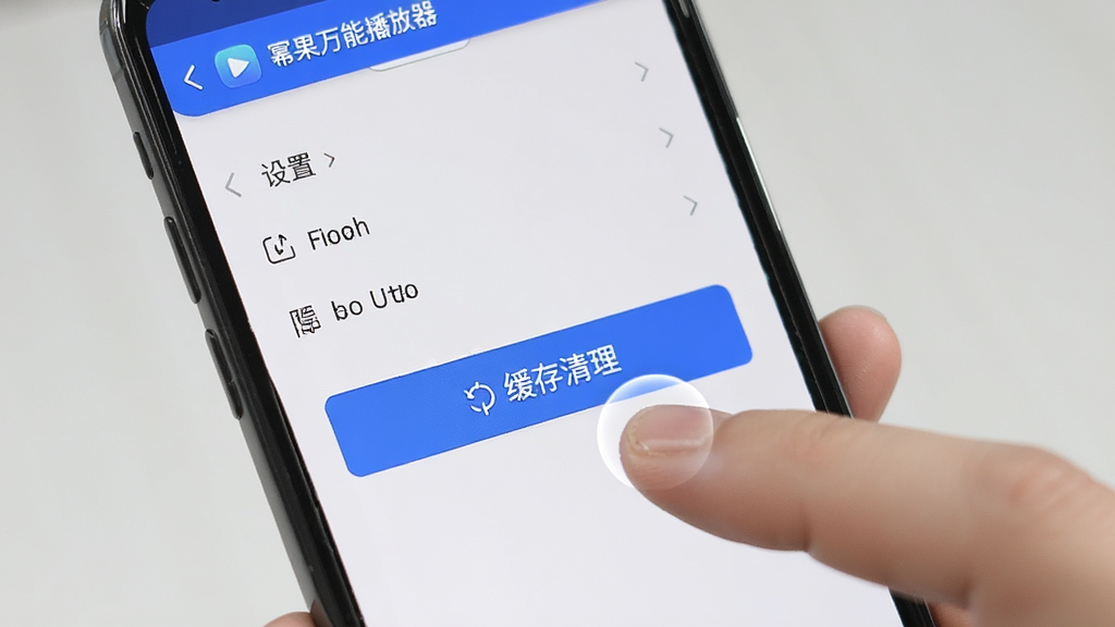 主体为“幂果万能播放器”在手机上的操作界面,显示设置菜单与缓存清理按钮,布局上下滑动,排版清爽,风格简约,细节包括手指点击动作,画质干净,无多余元素