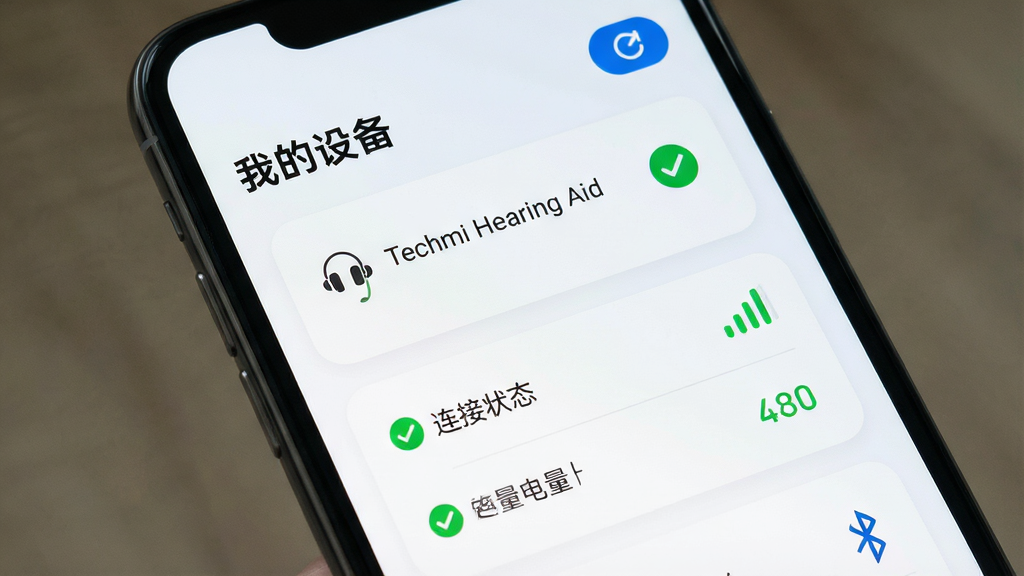 Techmi App �����豸���ӹ���ҳ�棬����Ϊ�ֻ���Ļ��ʾ������豸�б����ź�ǿ��ָʾ������Ϊ�б�ʽ�Ű棬�Ϸ��ǡ��ҵ��豸��������ˢ�°�ť���м��Ƕ���ͼ�����豸���ơ�Techmi Hearing Aid�����·�������״̬�������ʾ�����Ϊǳɫ��Լ��Ƭ��ƣ�ϸ�ڰ���Բ�Ǿ��ο�Ƭ����ɫ���ӳɹ���ʶ������ͼ�꣬���ʸ��壬�ɾ����޶���Ԫ��